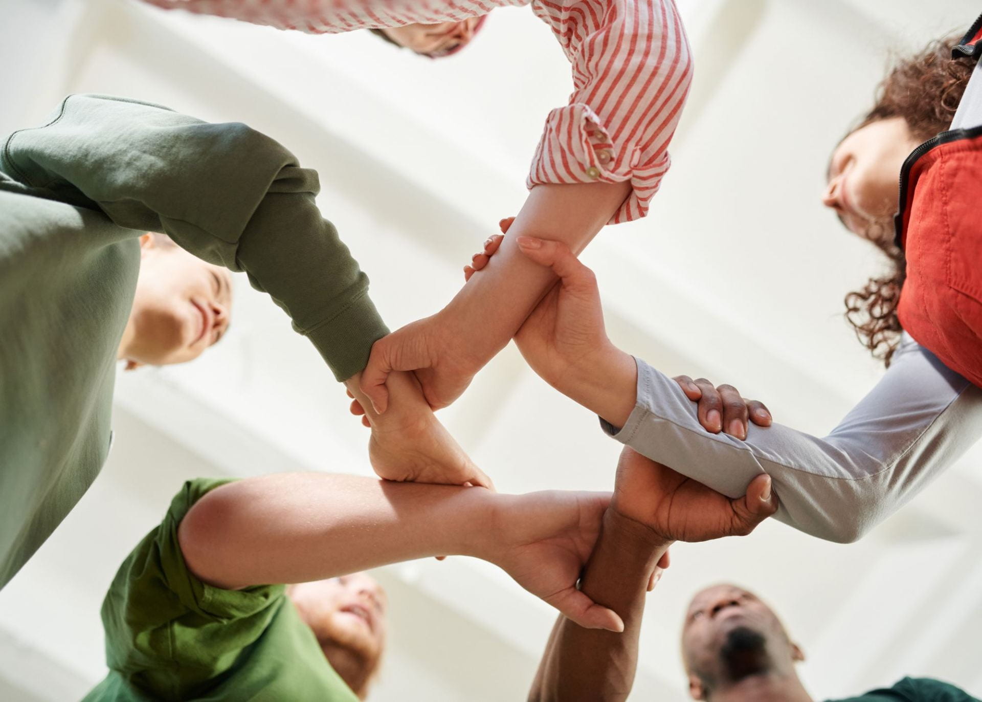 Diverse group of people grasping each other's wrists to form a circle